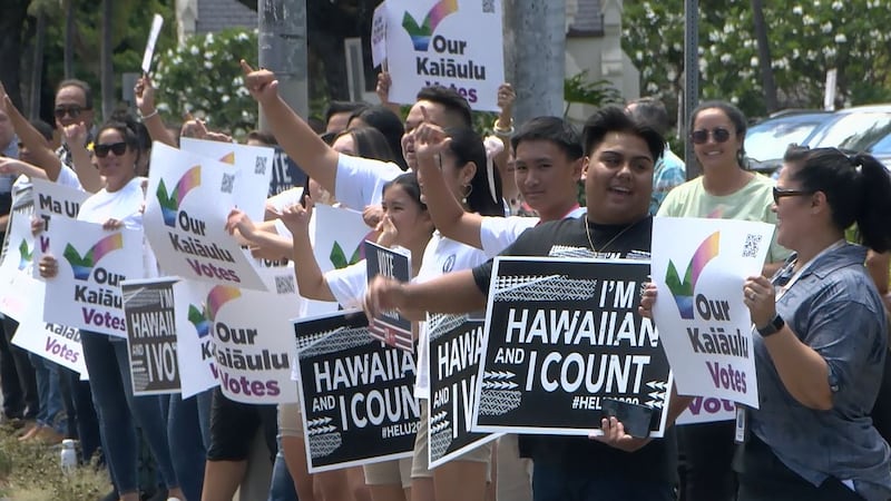 Native Hawaiian groups wave sign on King St., Honolulu