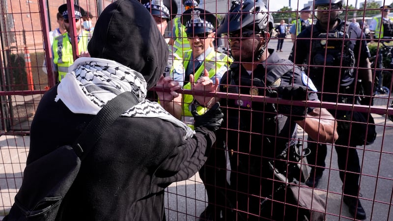 A protester tries to push through a fence surrounding the United Center during the Democratic...